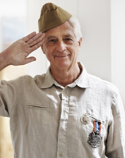 A senior war veteran looking at the camera wearing his uniform