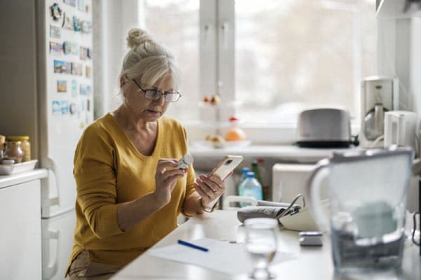 An older woman reviews the instructions on a prescription bottle to ensure medication safety for older adults.