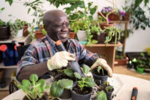 An older man in a wheelchair works with plants, one of many enriching activities for older adults with limited mobility.